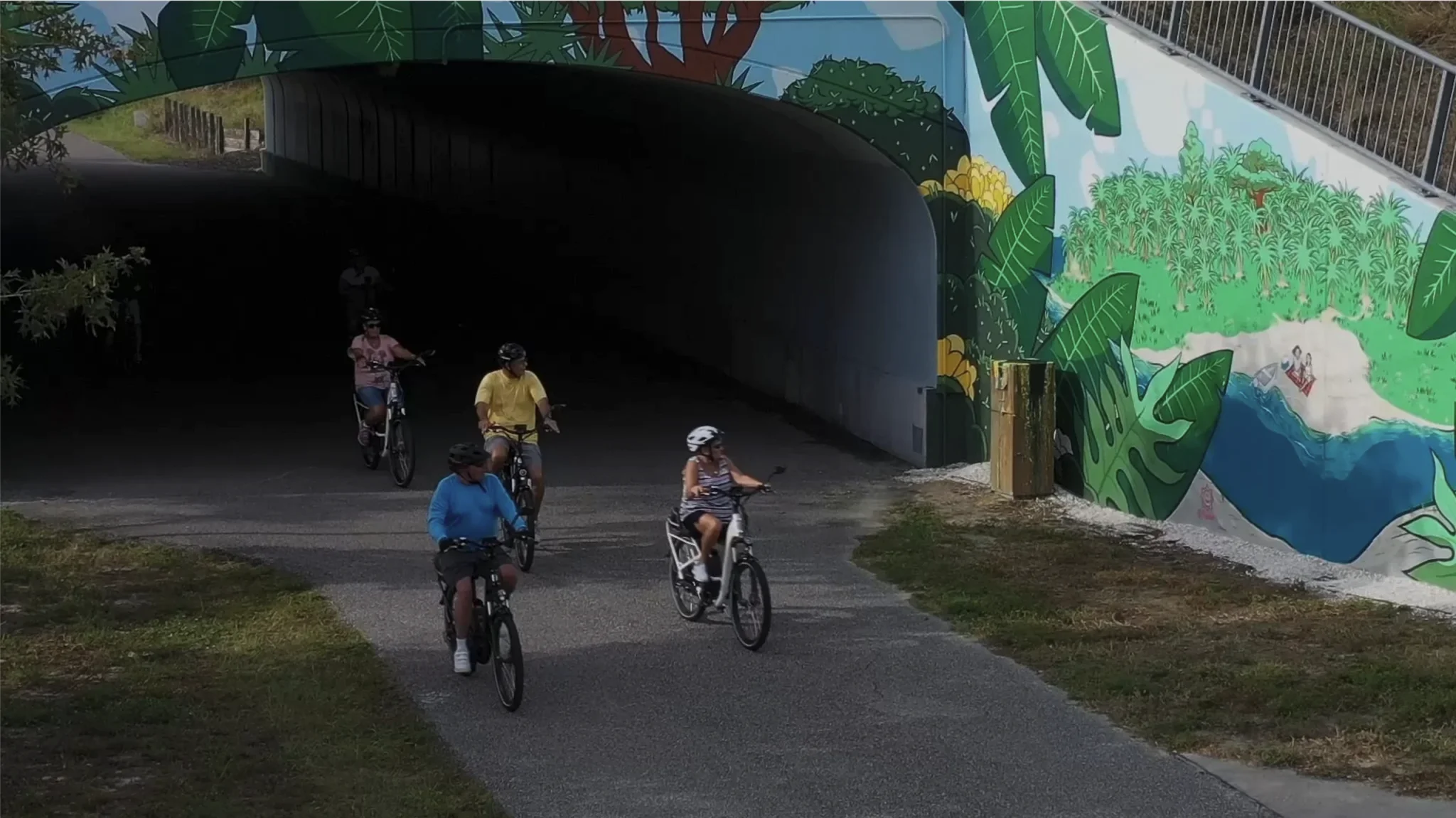 a group of bicyclists ride on the Pinellas Trail under the Alt-19 underpass